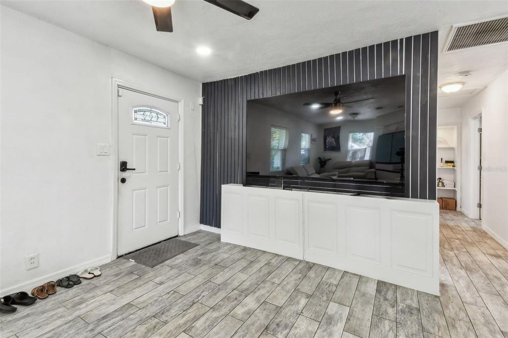 A living room features a white front door, wood-look tile floors, and a built-in media wall — 4005 W TYSON AVENUE, TAMPA, FL