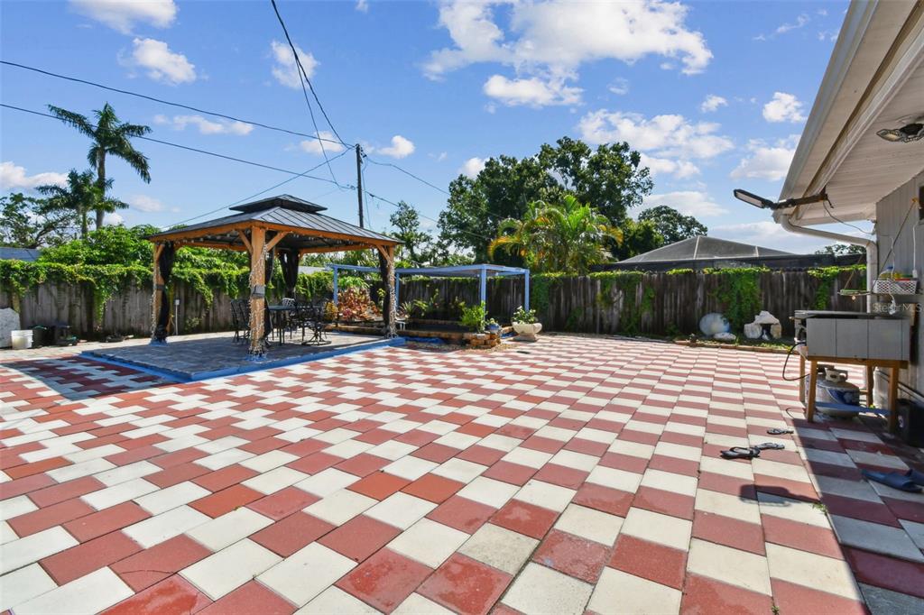 A backyard patio features a red and white checkered floor, a gazebo, and wooden fencing — 4005 W TYSON AVENUE, TAMPA, FL