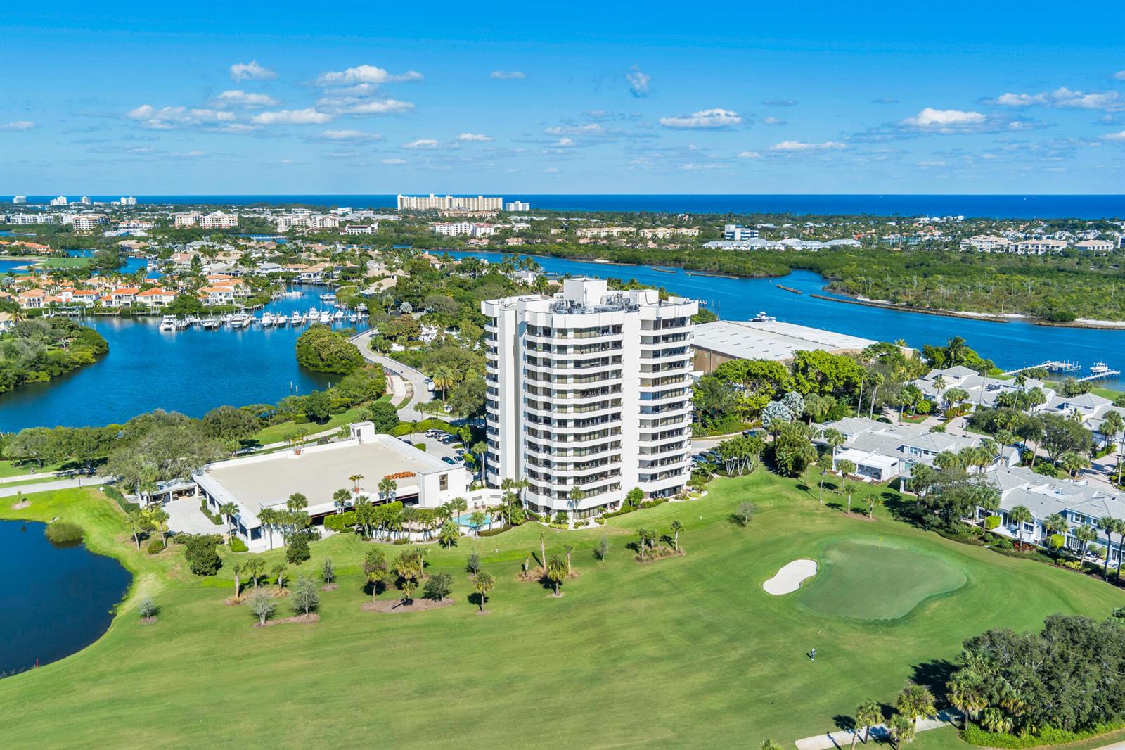 An aerial view shows a tall residential building surrounded by a golf course and waterways — 3322 Casseekey Island Road # 902, Jupiter FL 33477, JUPITER, FL