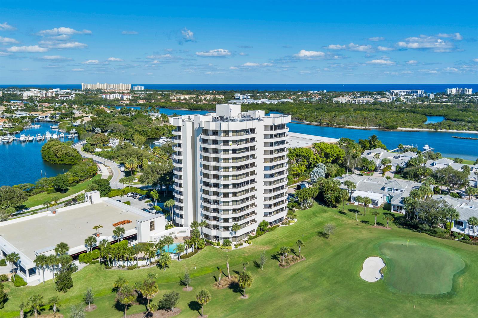 An aerial view shows a tall residential building situated on a golf course near water — 3322 Casseekey Island Road # 902, Jupiter FL 33477, JUPITER, FL