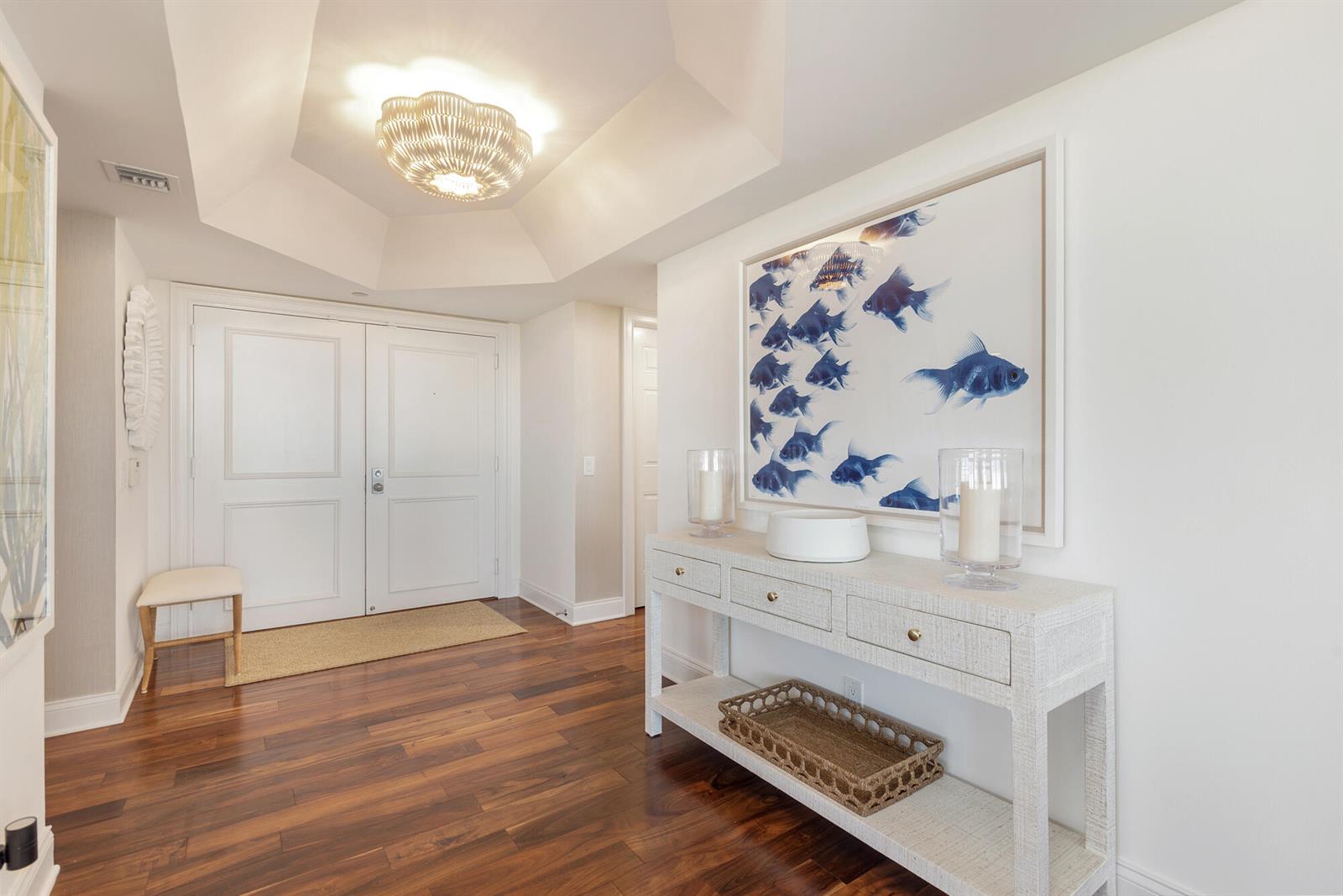 A bright entryway features a white console table, fish artwork, and a coffered ceiling — 3322 Casseekey Island Road # 902, Jupiter FL 33477, JUPITER, FL
