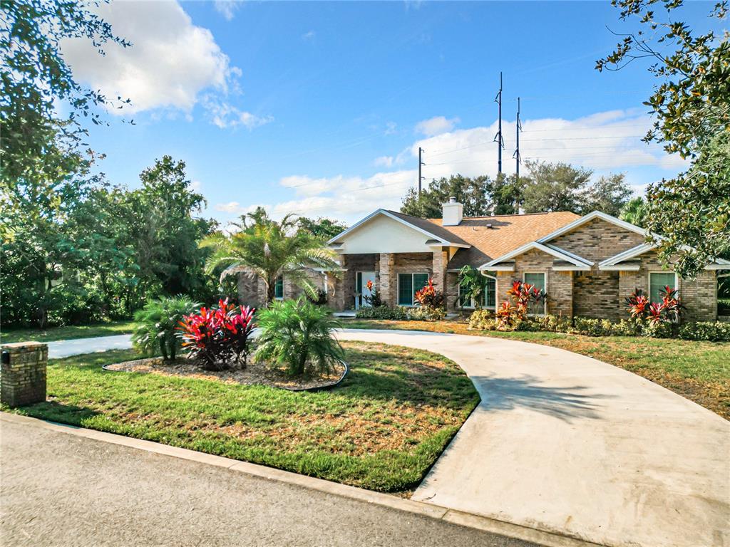 A single-story brick house with a curved concrete driveway and landscaped front yard — 8707 FERNWICKE COURT, ORLANDO, FL