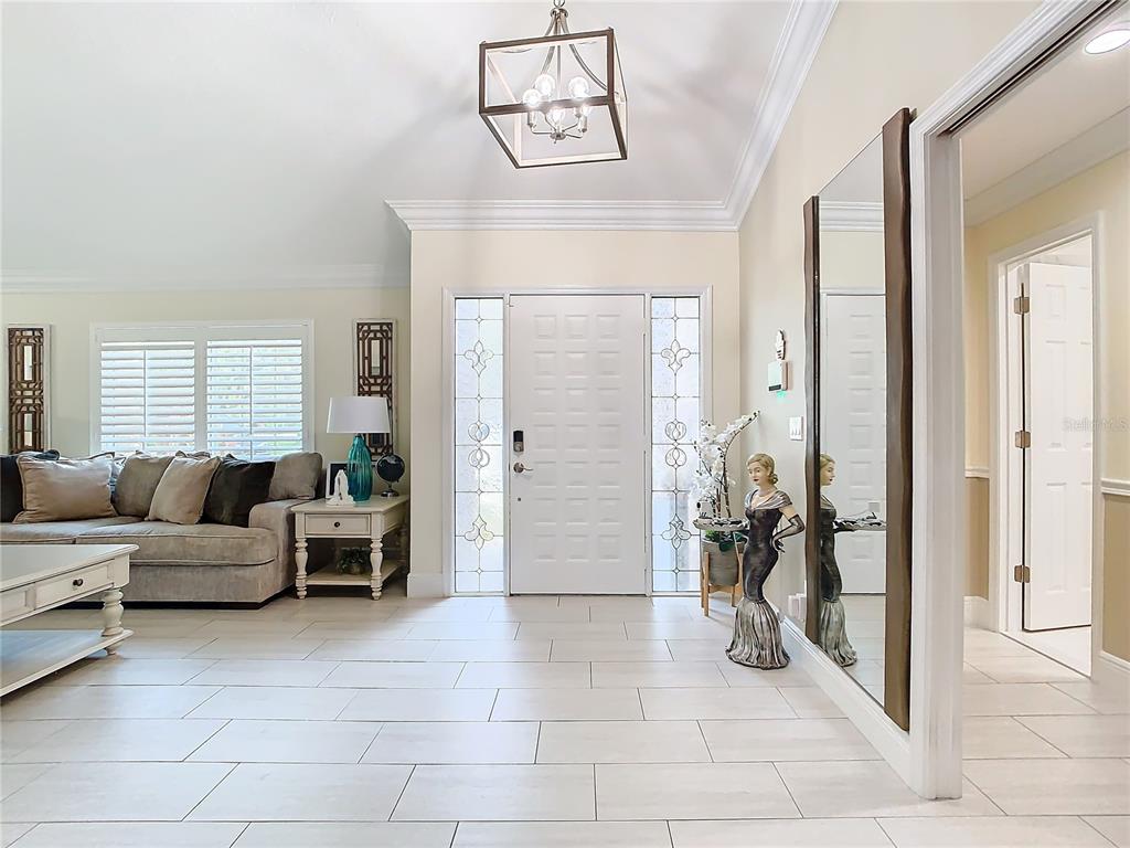 An entryway features light tile floors, a white front door with sidelights, and a mirror — 8707 FERNWICKE COURT, ORLANDO, FL