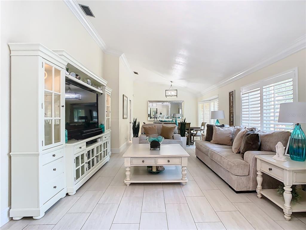 A living room features light tile floors, a large white entertainment center, and neutral furniture — 8707 FERNWICKE COURT, ORLANDO, FL