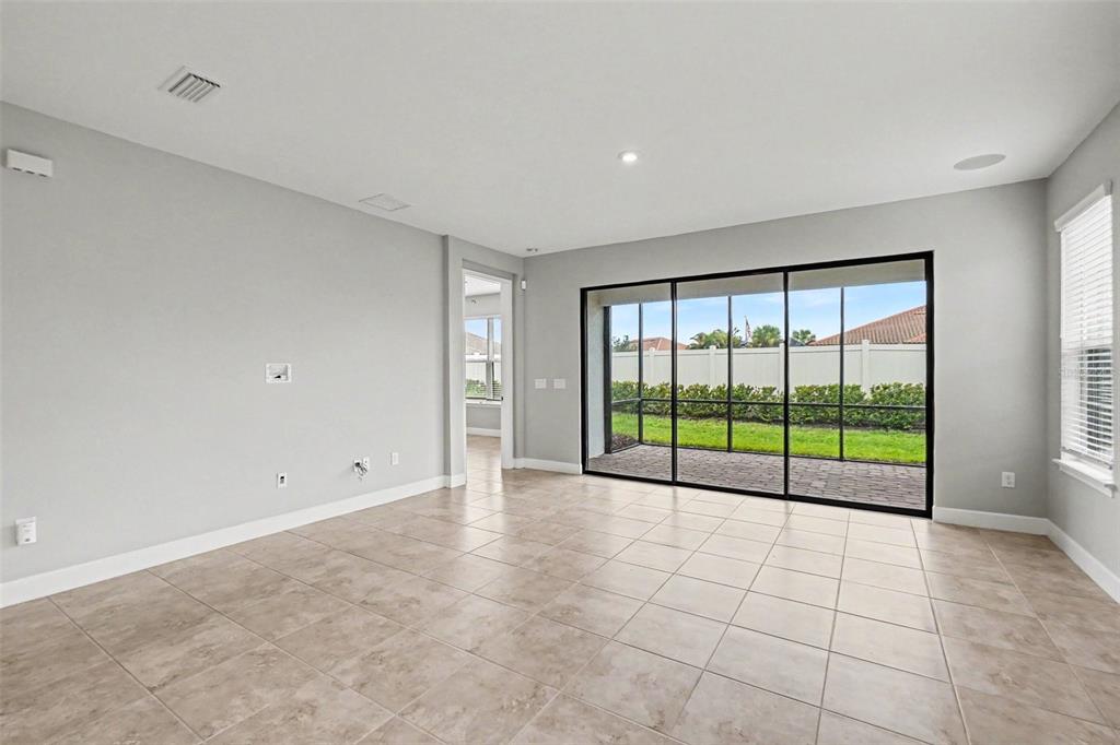 An empty room with light tile flooring, gray walls, and large sliding glass doors — 10930 WENDOVER DRIVE, PALMETTO, FL
