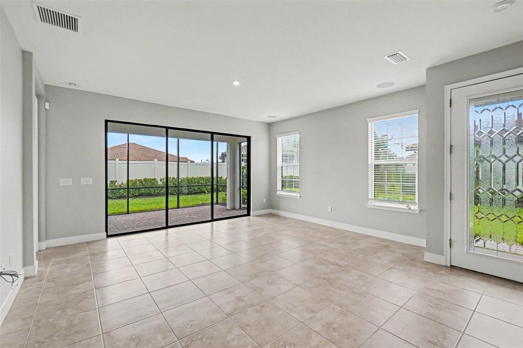 An empty room with light tile floors, sliding glass doors, and a glass-paneled exterior door — 10930 WENDOVER DRIVE, PALMETTO, FL
