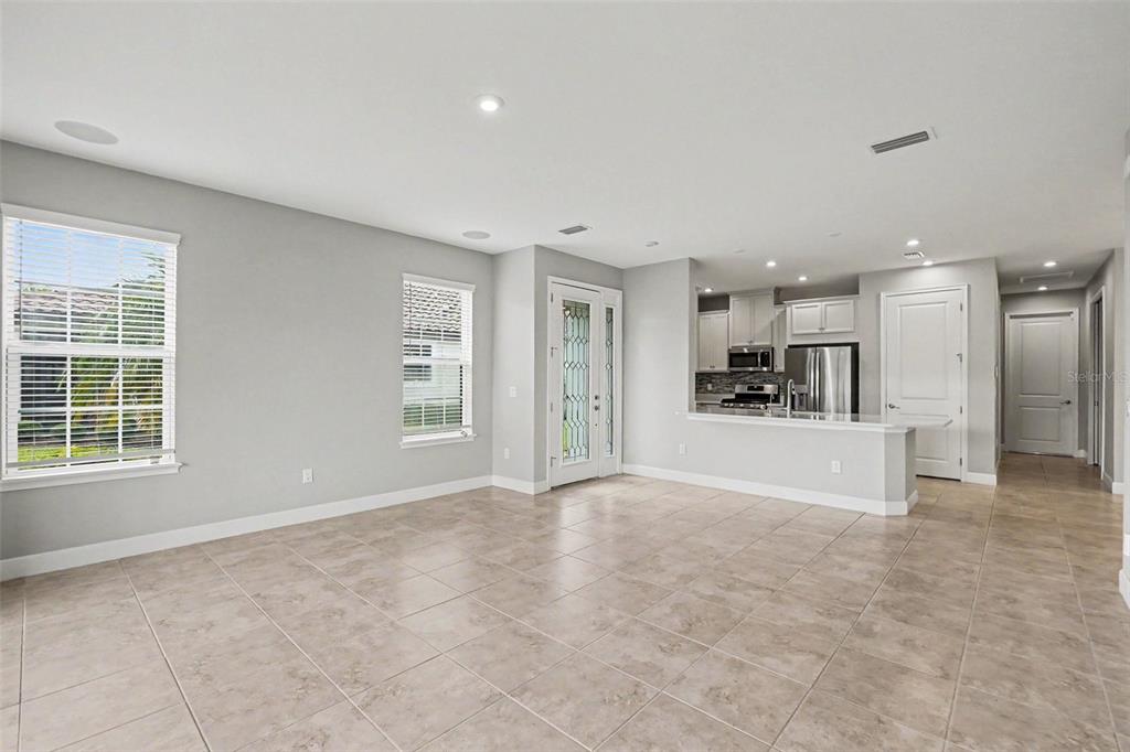 An open-concept living area features light gray walls, tile flooring, and an adjacent kitchen — 10930 WENDOVER DRIVE, PALMETTO, FL