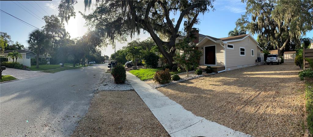A tan house with a gravel driveway and large oak trees in the front yard — 1832 WORRINGTON STREET, SARASOTA, FL
