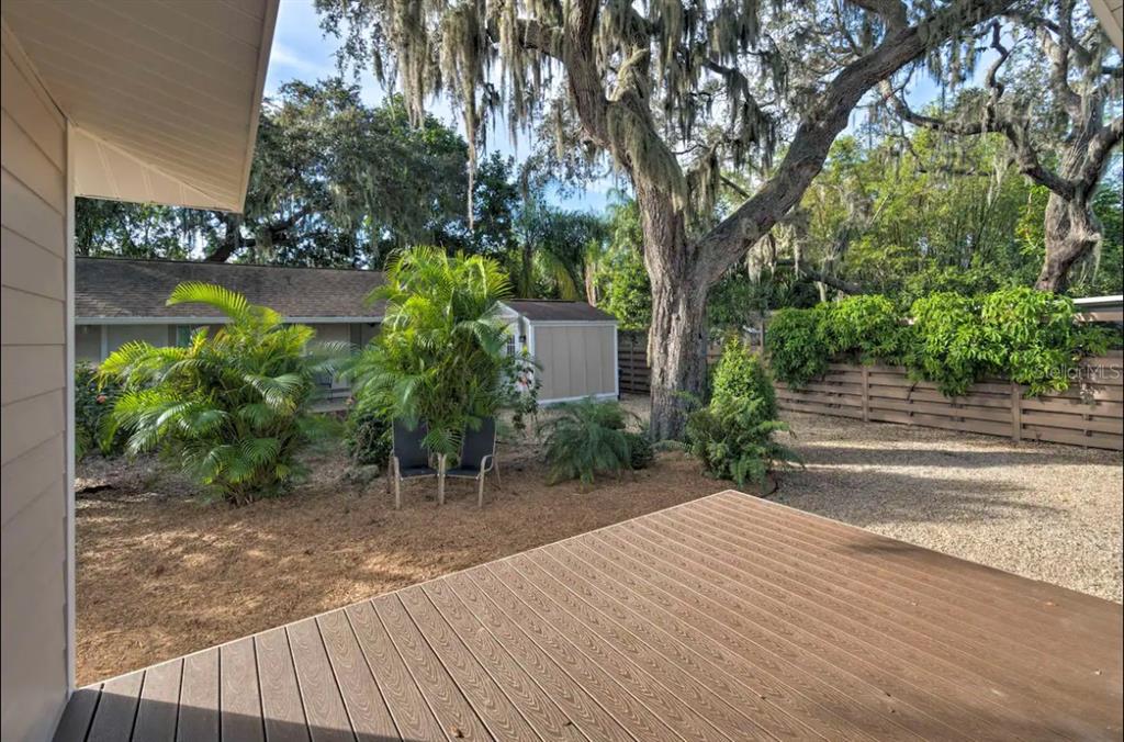 A wooden deck overlooks a backyard with a shed, palm trees, and a wooden fence — 1832 WORRINGTON STREET, SARASOTA, FL