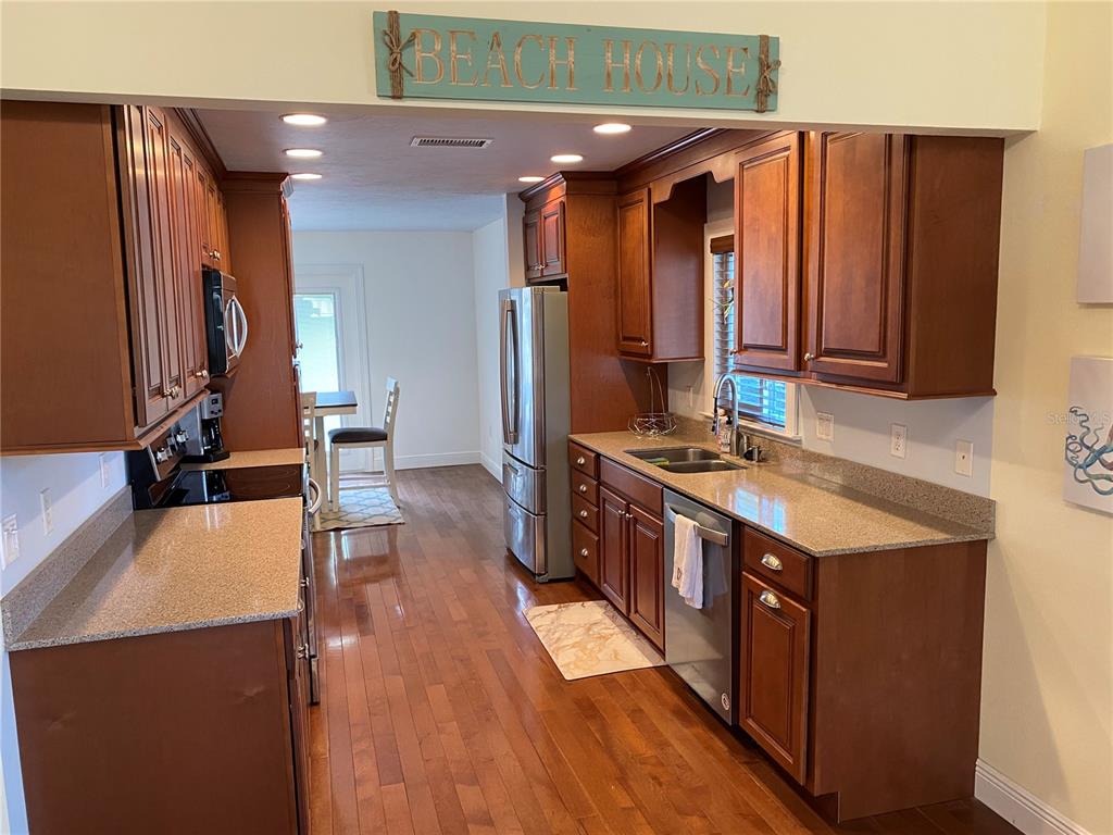 A kitchen with wood cabinets, granite countertops, stainless steel appliances, and hardwood flooring — 1832 WORRINGTON STREET, SARASOTA, FL