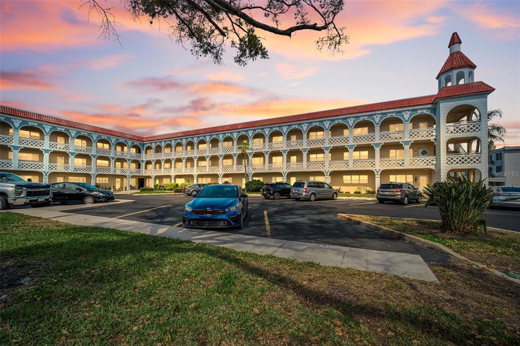 A multi-story apartment building with arched balconies and a corner tower under a sunset sky — 2404 FLORENTINE WAY UNIT 20, CLEARWATER, FL