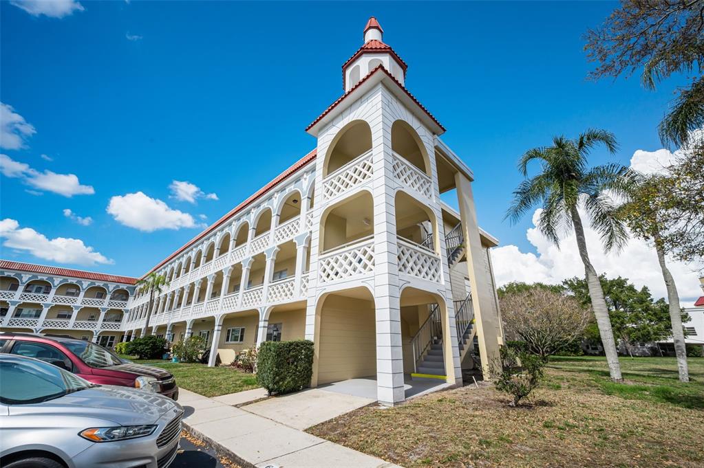 A multi-story apartment building with arched balconies and a corner tower under a blue sky — 2404 FLORENTINE WAY UNIT 20, CLEARWATER, FL