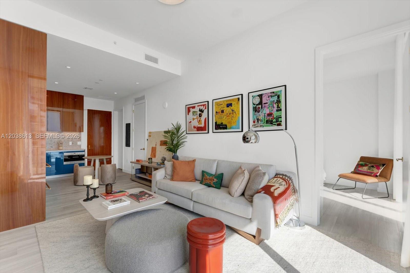 A modern living room features a light gray sofa, three framed artworks, and a kitchen area — 2655 S Bayshore Dr # 1606, Miami FL 33133, MIAMI, FL
