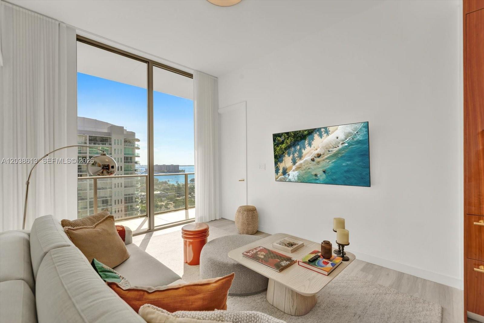 A living room features a sofa, a coffee table, a wall-mounted television, and balcony views — 2655 S Bayshore Dr # 1606, Miami FL 33133, MIAMI, FL