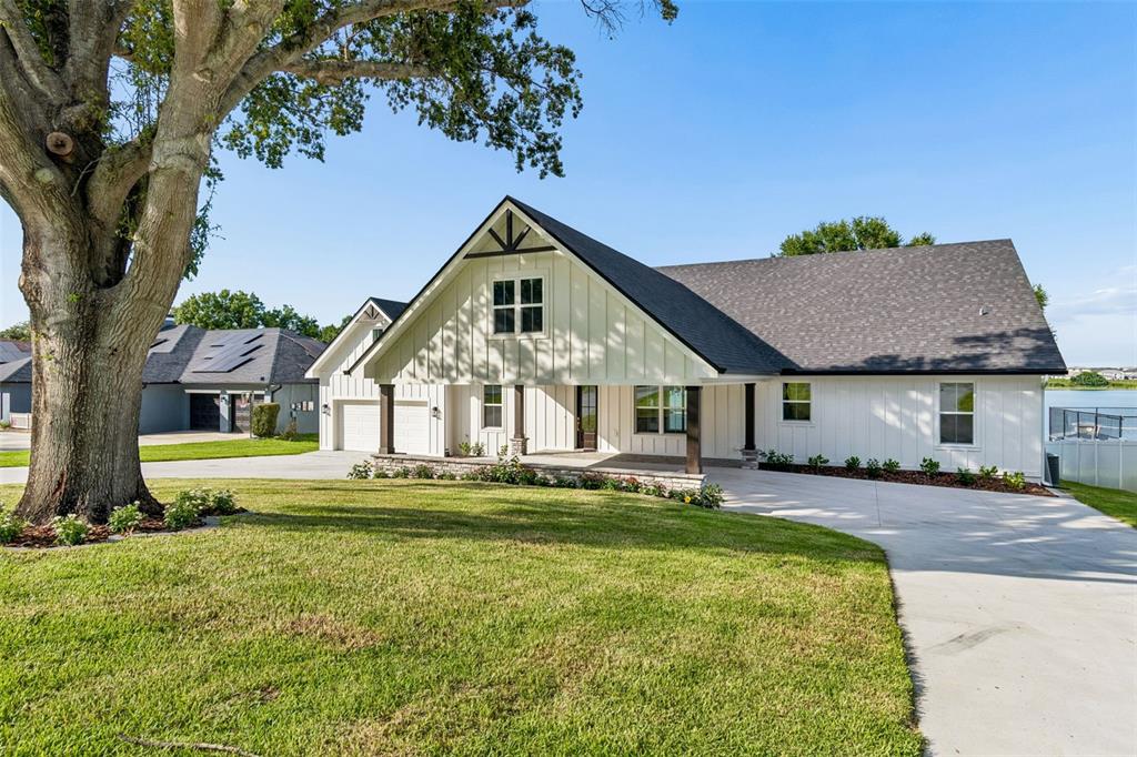 A white farmhouse-style home with a dark roof and a large tree in the yard — 5683 OLD BERKLEY ROAD, AUBURNDALE, FL