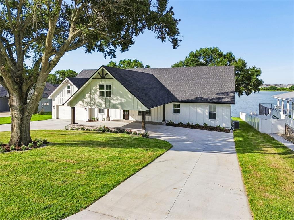 A white farmhouse-style house with a large covered porch sits beside a lake — 5683 OLD BERKLEY ROAD, AUBURNDALE, FL