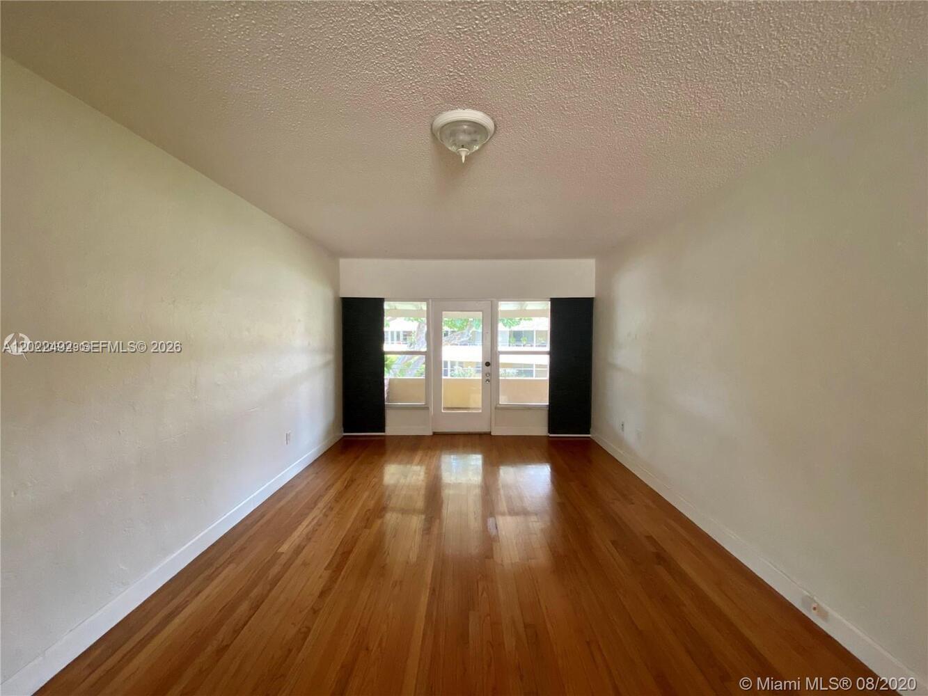 An empty room features hardwood floors, white walls, a ceiling light, and a glass door — 30 Park Dr # 16, Bal Harbour FL 33154, BAL HARBOUR, FL