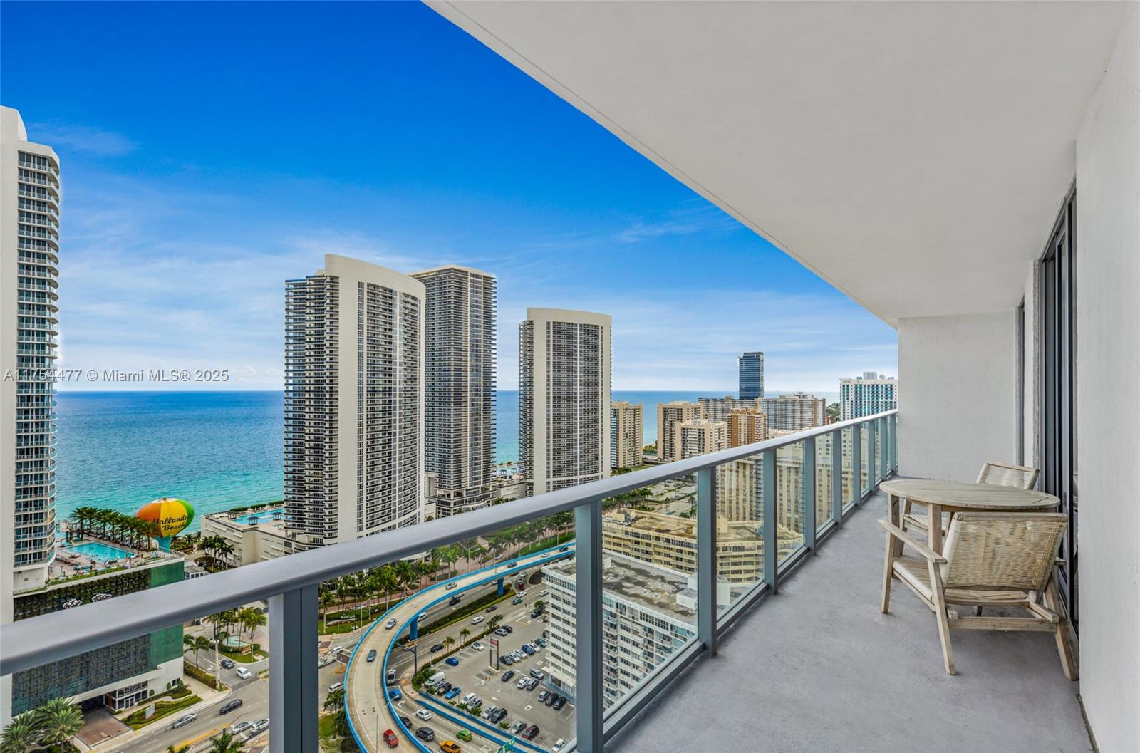 A balcony with a table and chairs overlooks a coastal city with high-rise buildings — 4010 S Ocean Dr # R2505, Hollywood FL 33019, HOLLYWOOD, FL