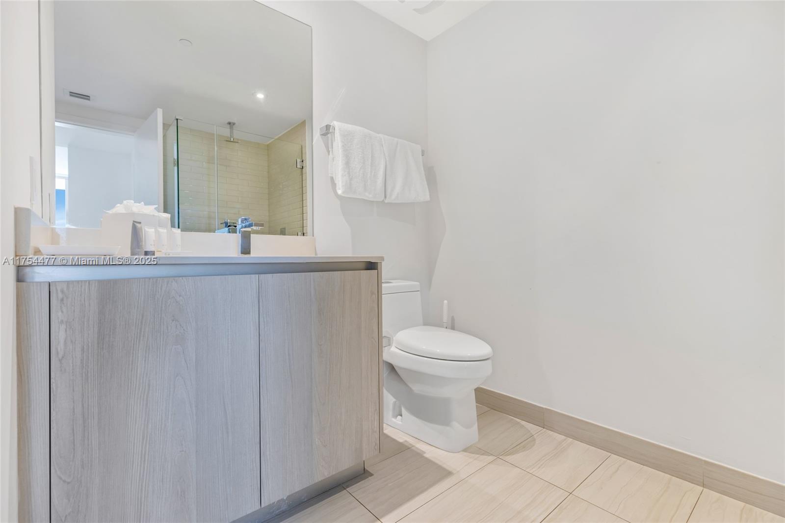 A modern bathroom features a light wood vanity, a white toilet, and a glass-enclosed shower — 4010 S Ocean Dr # R2505, Hollywood FL 33019, HOLLYWOOD, FL