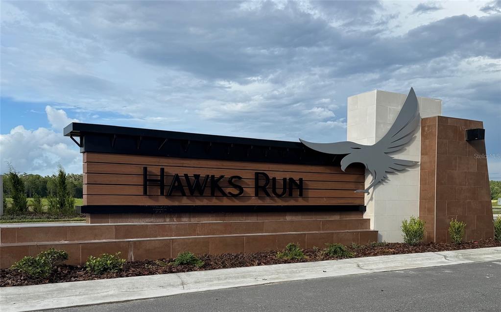 A large, modern monument sign for Hawks Run stands against a cloudy blue sky — 2677 BROADWING STREET, KISSIMMEE, FL
