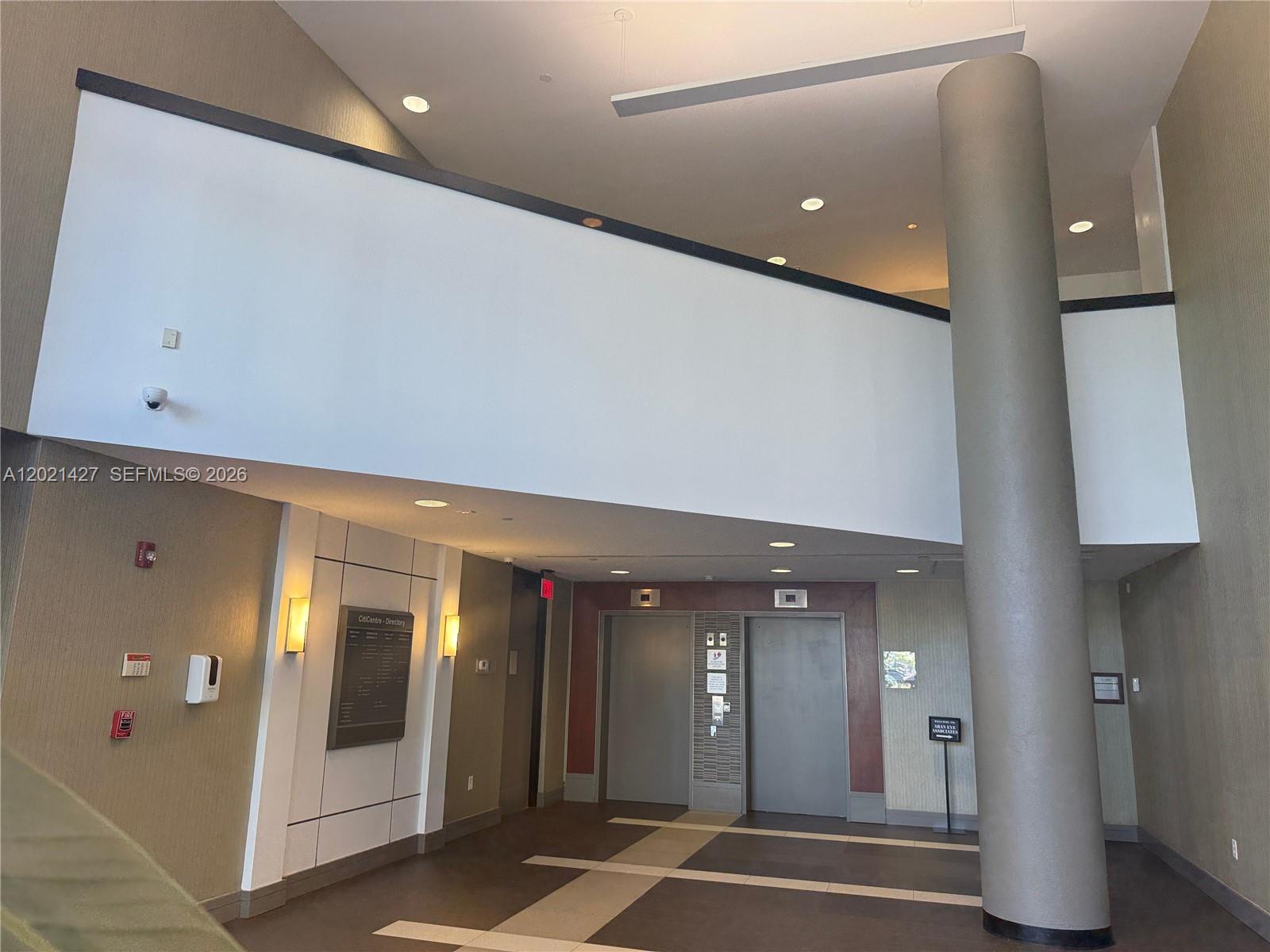A modern building lobby features a large central pillar, two elevators, and a directory sign — 290 NW 165th St # 700, Miami FL 33169, MIAMI, FL