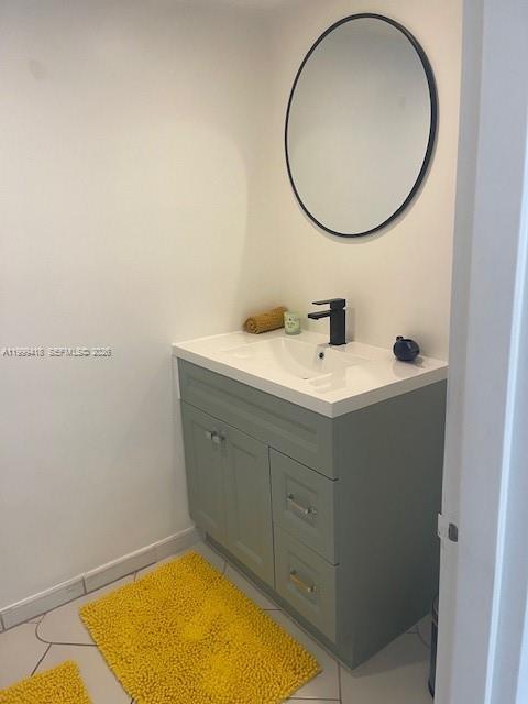 A bathroom features a sage green vanity with a white sink, black faucet, and round mirror — 900 Bay Dr # 311, Miami Beach FL 33141, MIAMI BEACH, FL