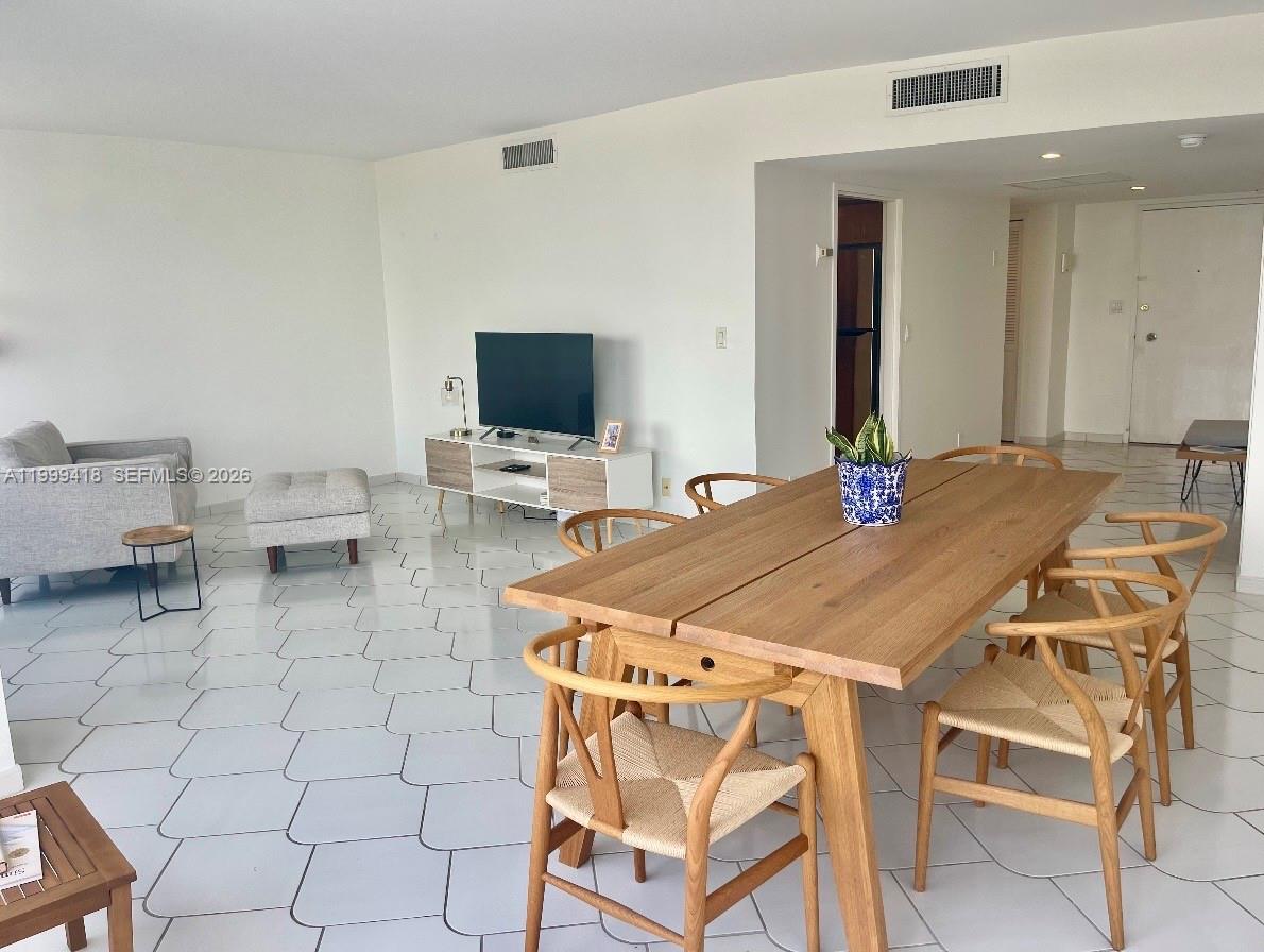 A dining area with a wooden table and chairs sits in front of a living room — 900 Bay Dr # 311, Miami Beach FL 33141, MIAMI BEACH, FL