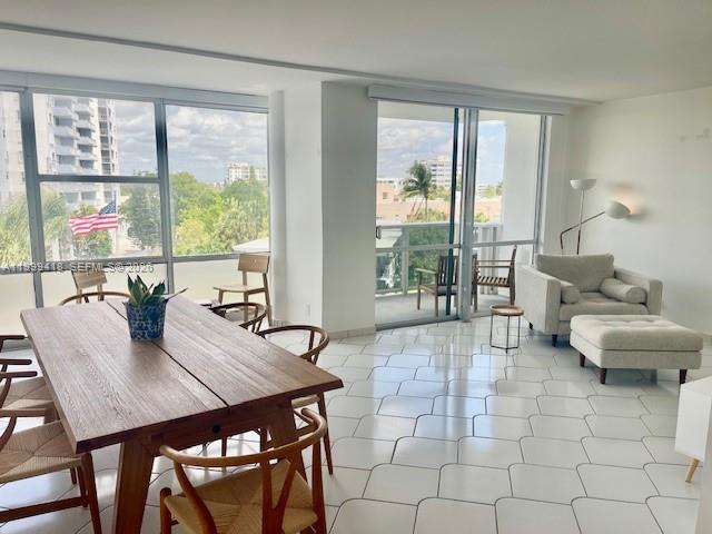 A bright living and dining area features white tile floors, floor-to-ceiling windows, and a balcony — 900 Bay Dr # 311, Miami Beach FL 33141, MIAMI BEACH, FL