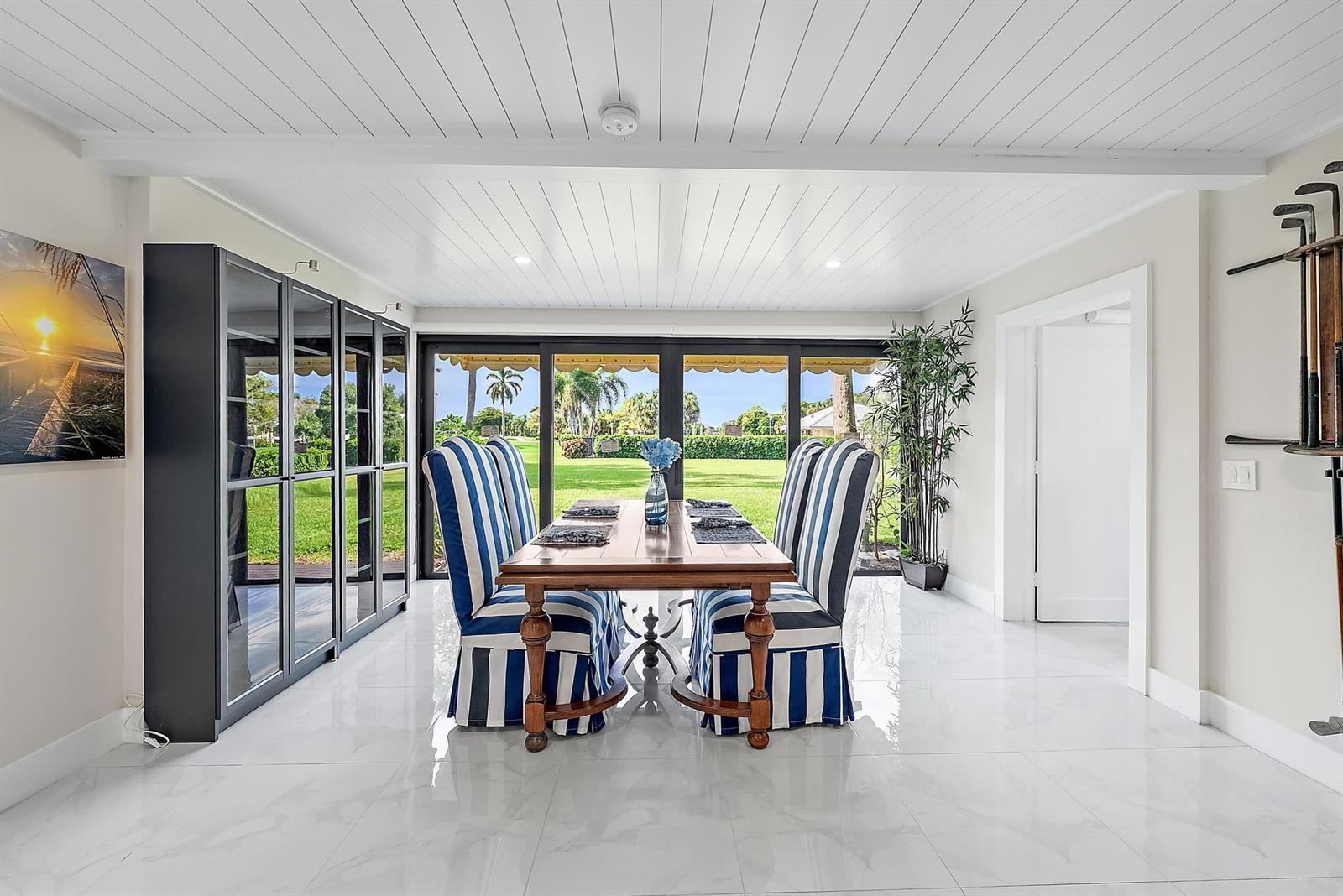 A dining room features a wooden table with striped chairs, white tile floors, and sliding doors — 3693 Quail Ridge Drive # B, Boynton Beach FL 33436, BOYNTON BEACH, FL