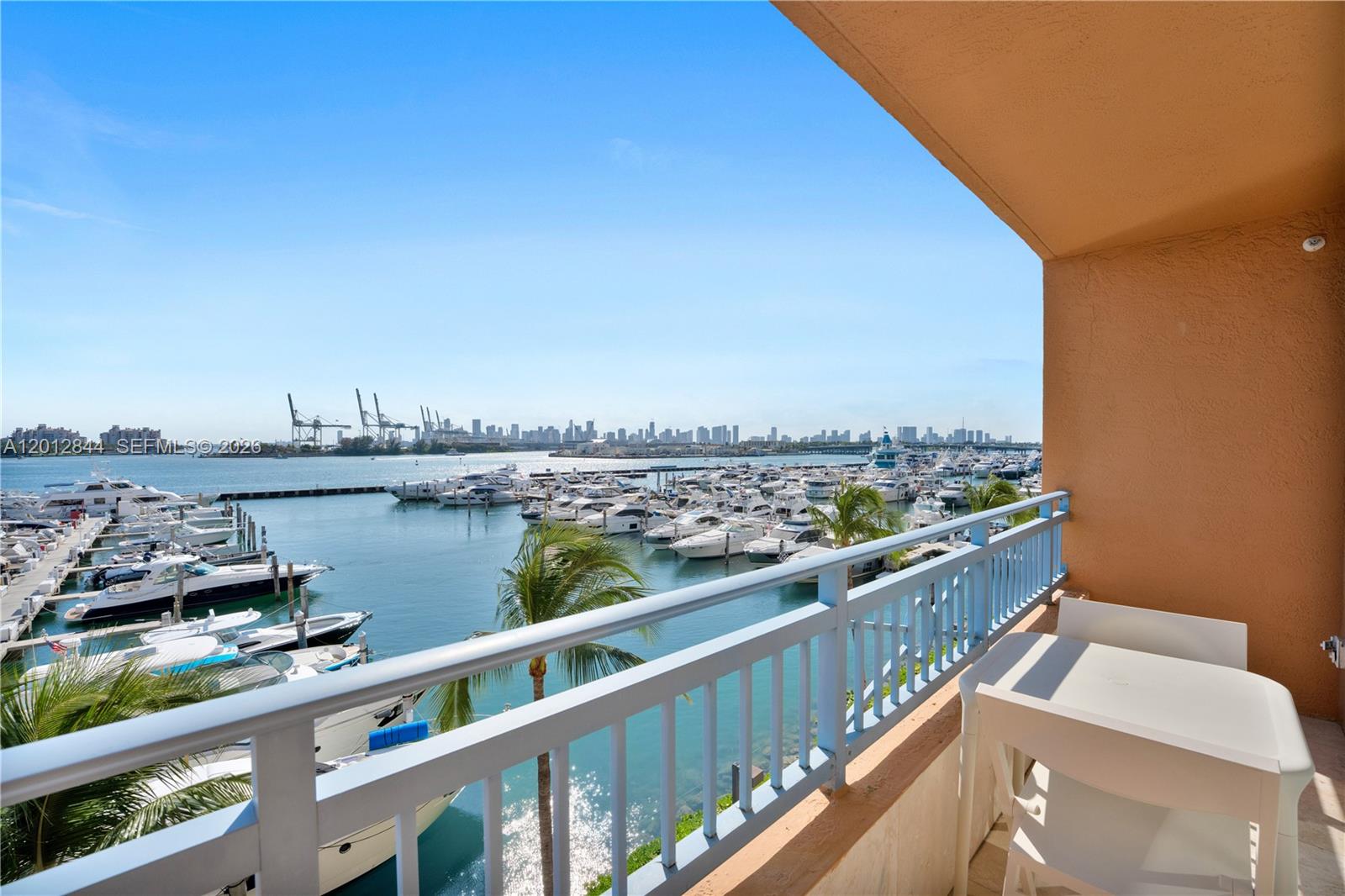A balcony overlooks a marina filled with boats and a distant city skyline — 90 Alton Rd # 3, Miami Beach FL 33139, MIAMI BEACH, FL