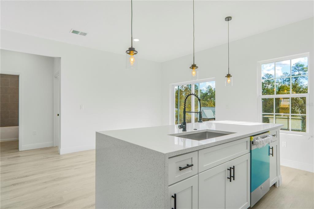A kitchen island with a sink and pendant lighting sits in a bright, modern room — 2632 SW 162ND STREET ROAD, OCALA, FL