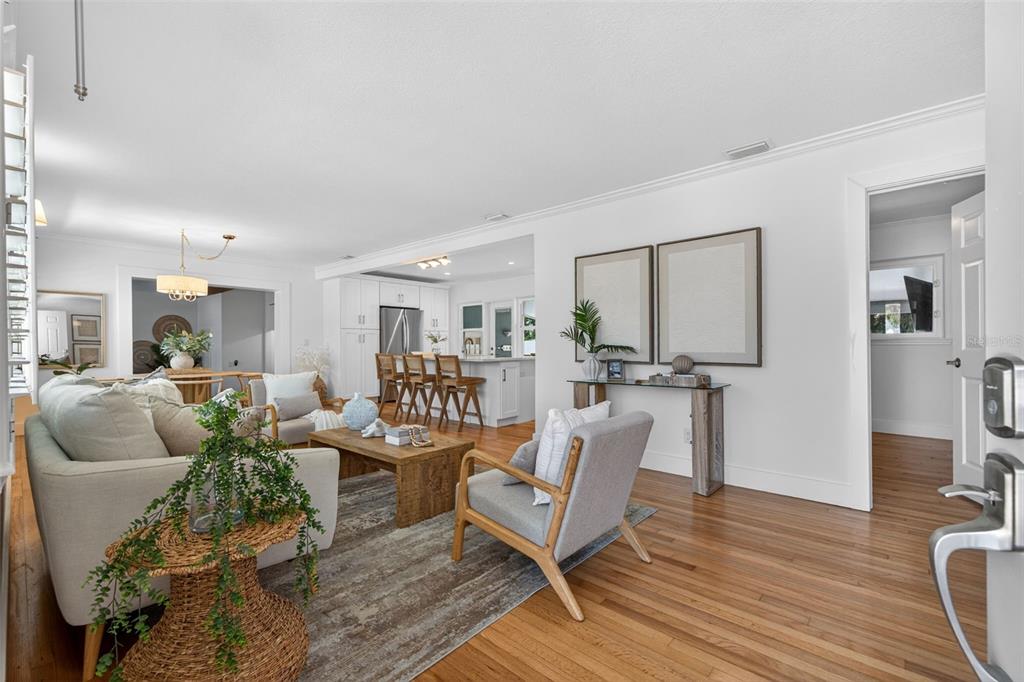A bright living room with hardwood floors, a sofa, an armchair, and an open kitchen — 976 NARCISSUS AVENUE, CLEARWATER BEACH, FL