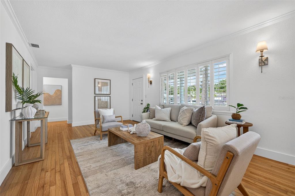 A bright living room features hardwood floors, a neutral sofa, two armchairs, and plantation shutters — 976 NARCISSUS AVENUE, CLEARWATER BEACH, FL