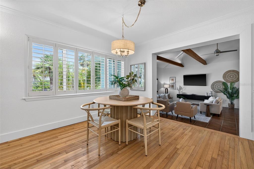 A dining area with a round wooden table and chairs sits before a living room — 976 NARCISSUS AVENUE, CLEARWATER BEACH, FL