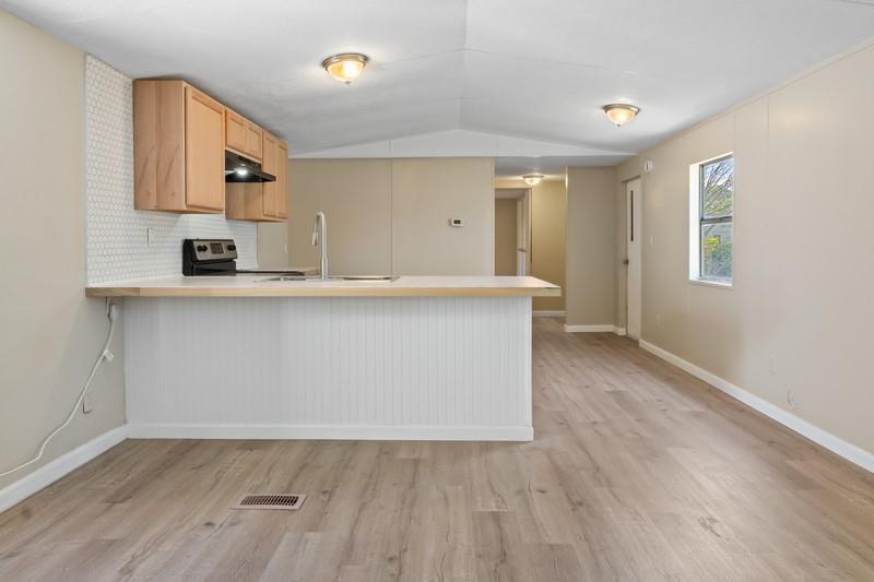 A kitchen with light wood cabinets, a white peninsula, and light-colored wood-look flooring — MERRITT ISLAND, FL