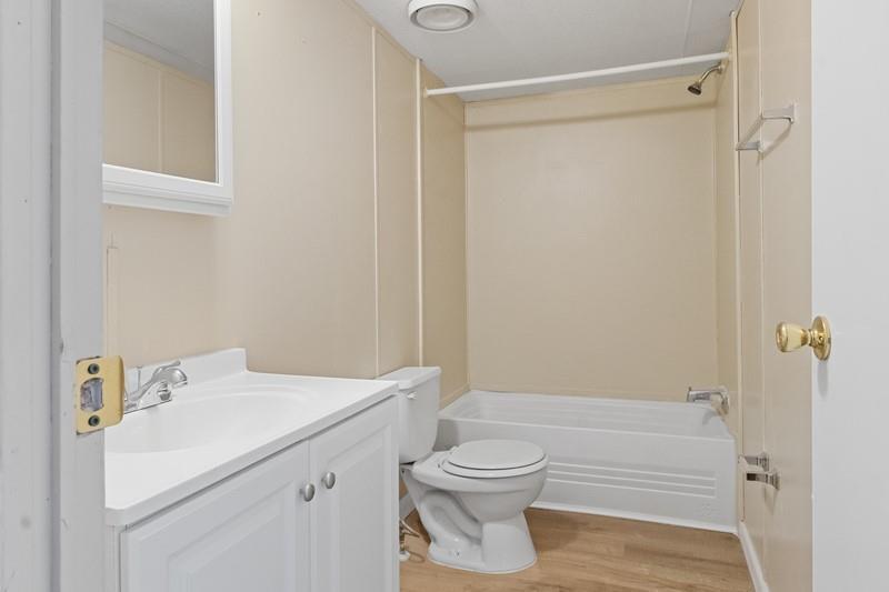 A bathroom features a white vanity, a toilet, and a tub-shower combo with beige walls — MERRITT ISLAND, FL