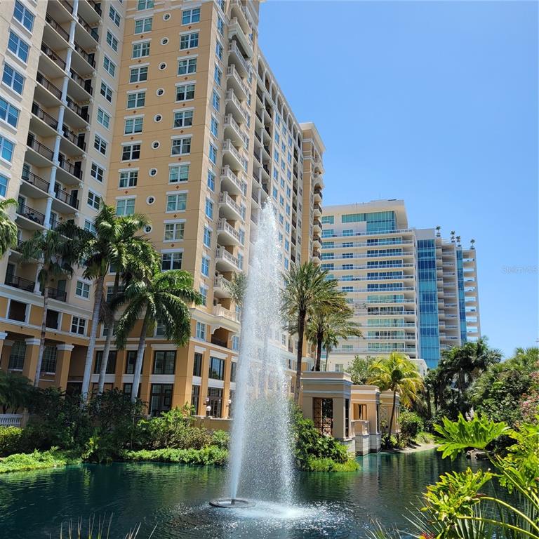 A tall, tan apartment building stands beside a pond with a large water fountain — 750 N TAMIAMI TRAIL UNIT 1404, SARASOTA, FL