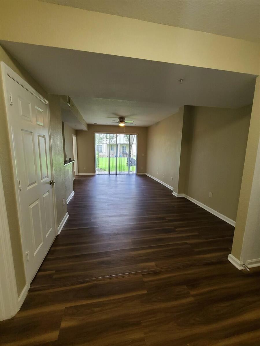 An empty living area with wood-look flooring, a ceiling fan, and sliding glass patio doors — 1955 Freeport Drive, Riviera Beach FL 33404, RIVIERA BEACH, FL