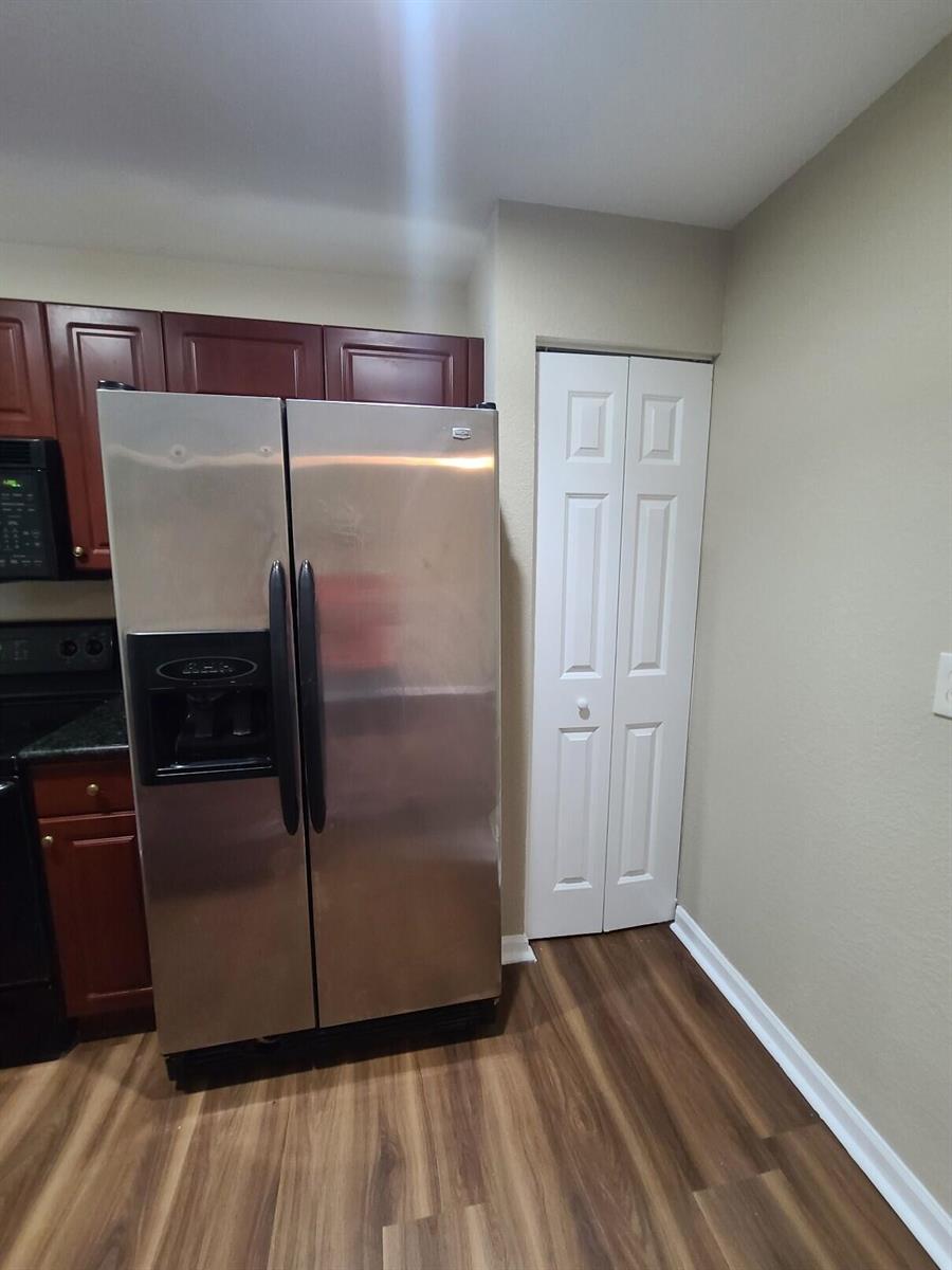 A stainless steel refrigerator stands next to a white bi-fold closet door in a kitchen — 1955 Freeport Drive, Riviera Beach FL 33404, RIVIERA BEACH, FL