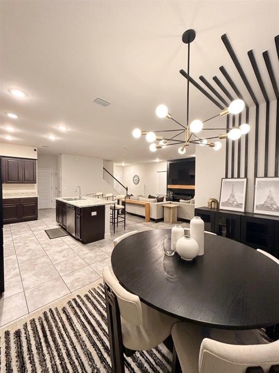 A dining area with a modern chandelier overlooks an open-concept kitchen and living room — 13058 OGDEN GLADE ROAD, DADE CITY, FL