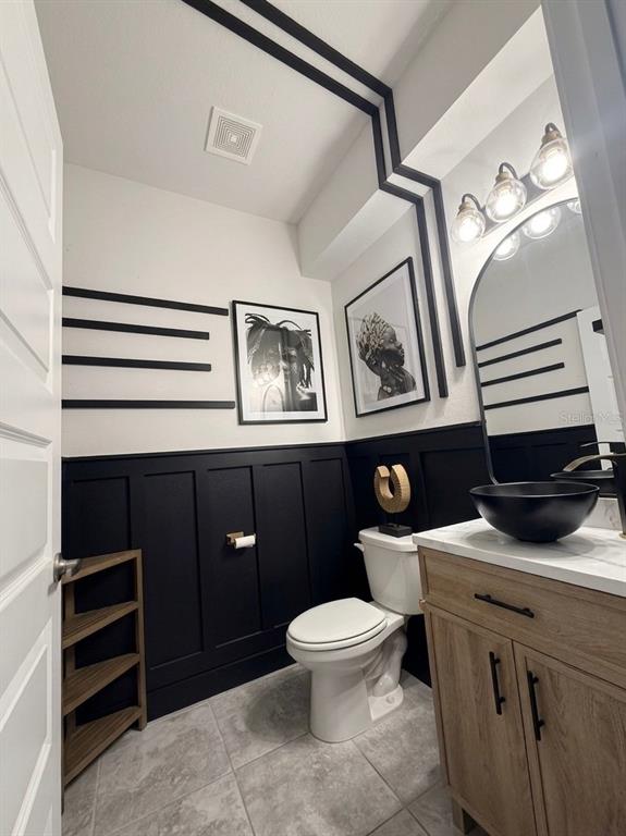 A powder room features black wainscoting, geometric wall trim, a wood vanity, and a vessel sink — 13058 OGDEN GLADE ROAD, DADE CITY, FL