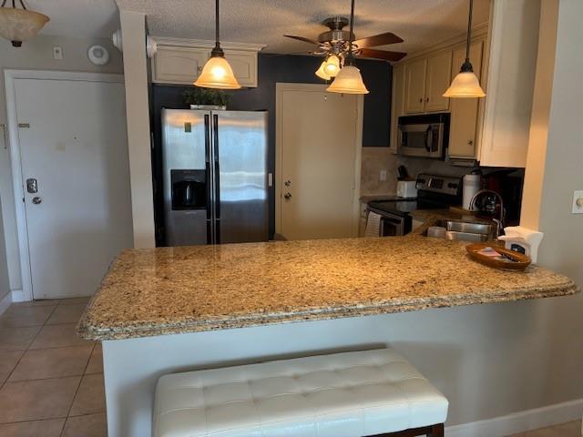 A kitchen features a granite breakfast bar, stainless steel refrigerator, and three hanging pendant lights — 133 N Pompano Beach Boulevard # 209, Pompano Beach FL 33062, POMPANO BEACH, FL