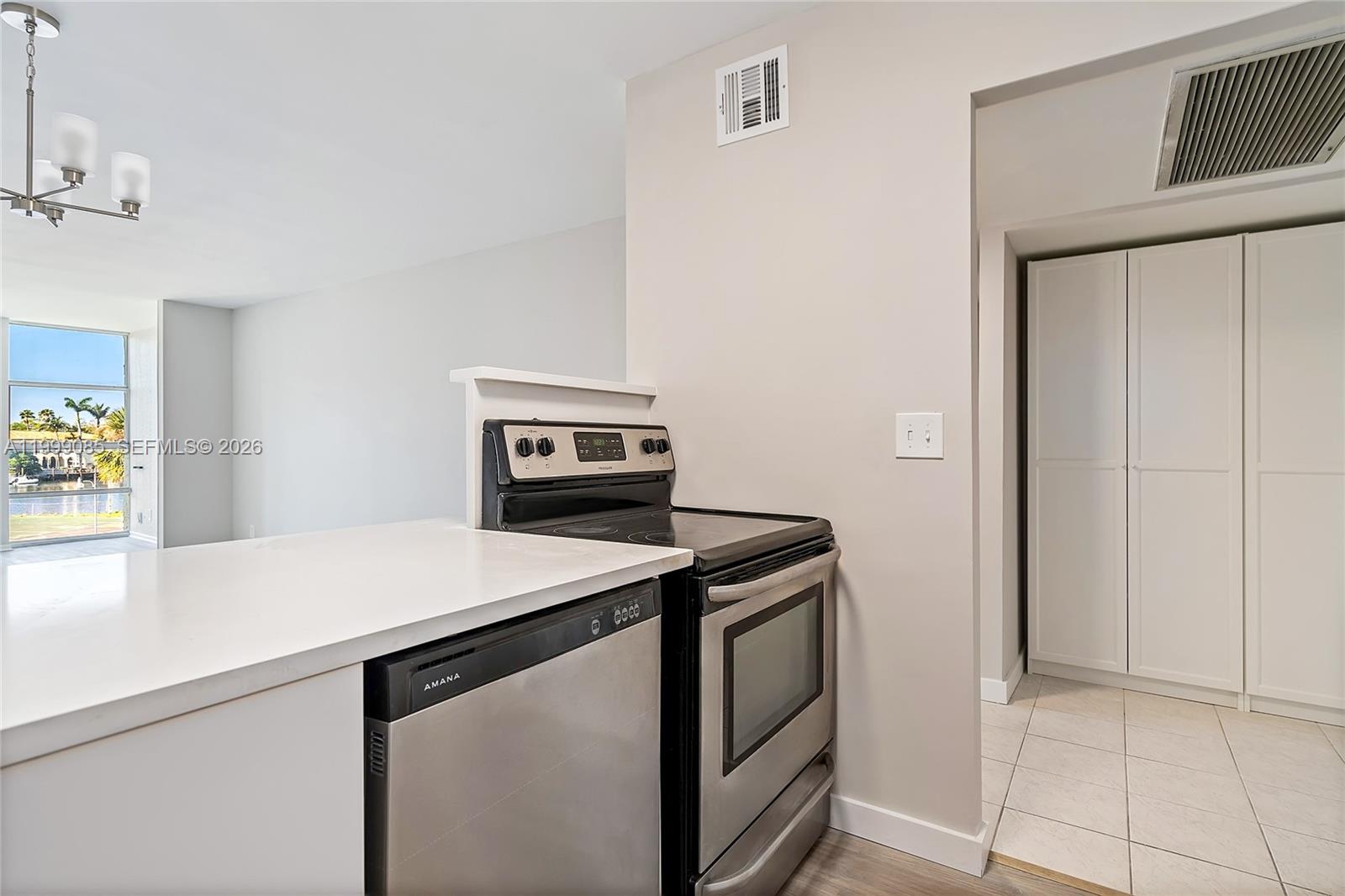 A kitchen features stainless steel appliances, white countertops, and a view of a waterfront area — 701 Three Islands Blvd # 316, Hallandale Beach FL 33009, HALLANDALE BEACH, FL
