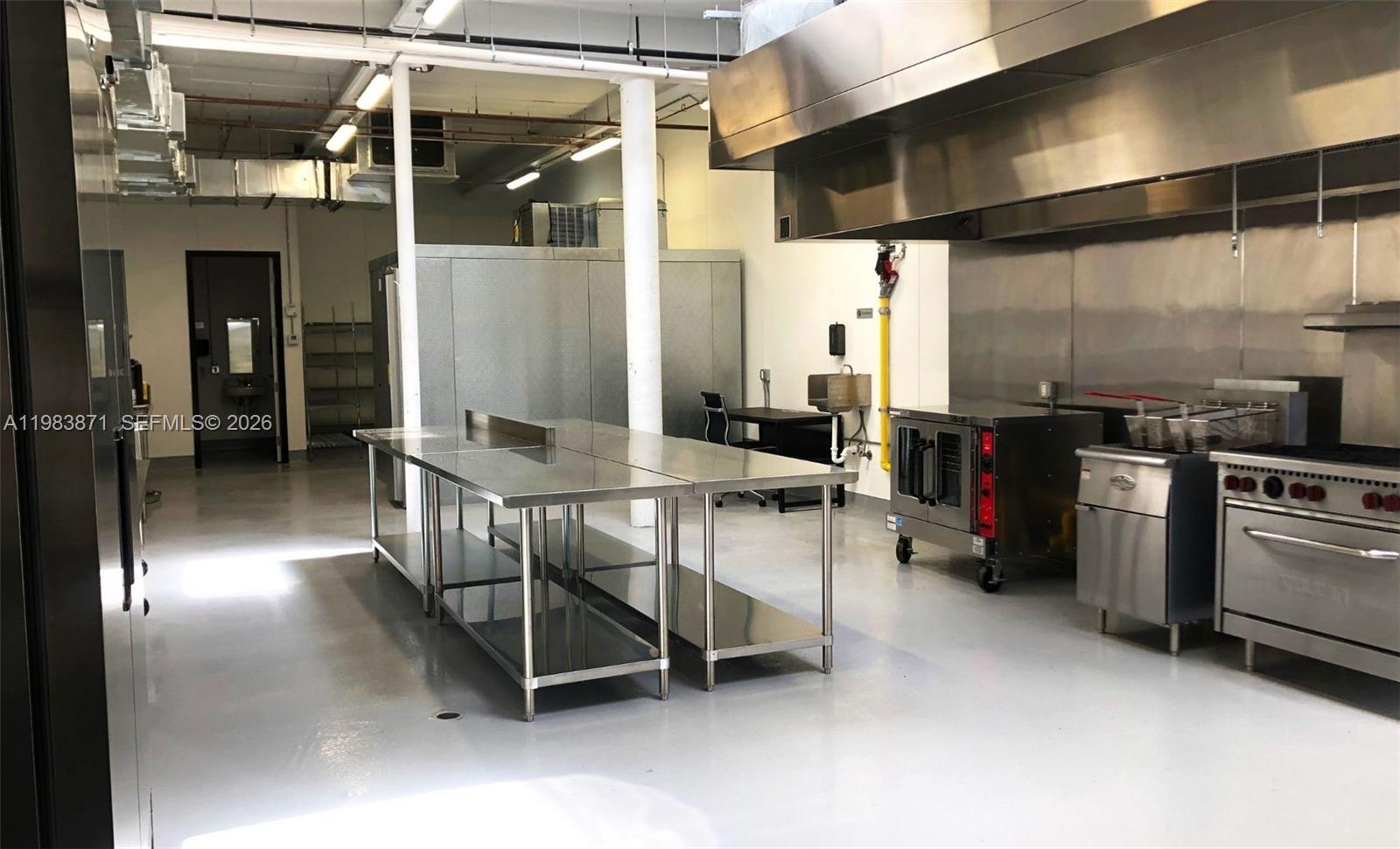A commercial kitchen features stainless steel prep tables, industrial appliances, and a large ventilation hood — 7700 NW 7th Ave, Miami FL 33150, MIAMI, FL