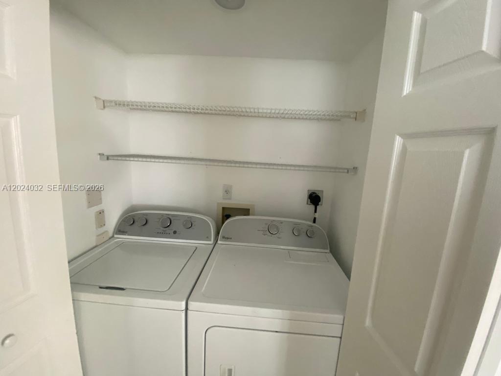 A laundry closet contains a white top-loading washer and dryer with wire shelving above — 1155 Brickell Bay Dr # 1202, Miami FL 33131, MIAMI, FL
