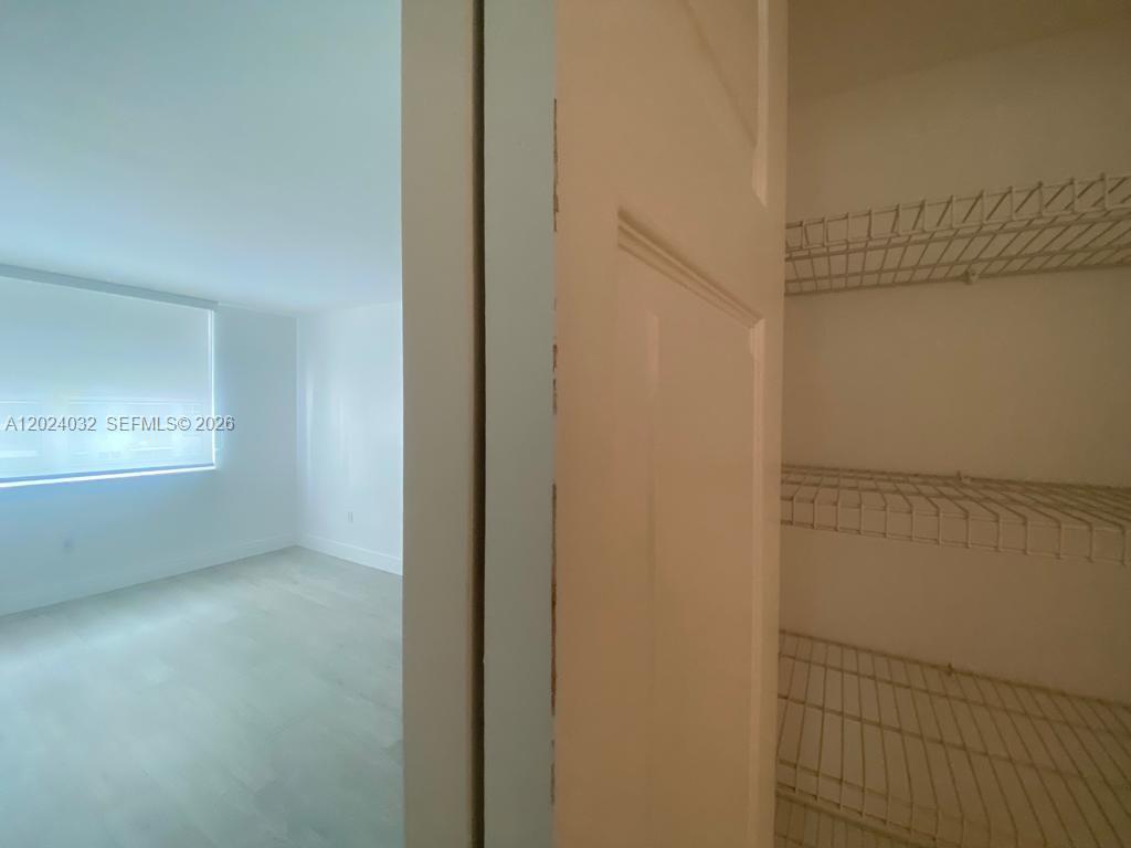 A view from a closet with wire shelving into an empty room with light flooring — 1155 Brickell Bay Dr # 1202, Miami FL 33131, MIAMI, FL