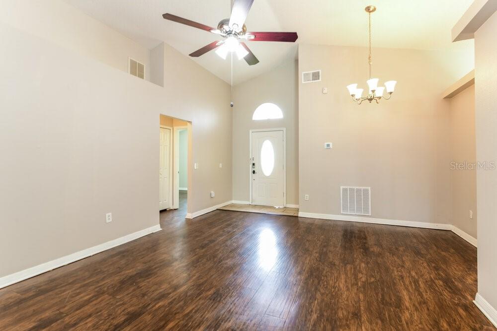 A living room with high ceilings, dark wood flooring, a ceiling fan, and a chandelier — 1129 PINEDALE DRIVE, DAVENPORT, FL