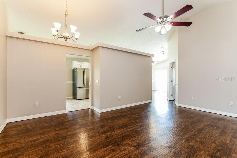 A living room with dark wood flooring, a ceiling fan, and a view into the kitchen — 1129 PINEDALE DRIVE, DAVENPORT, FL