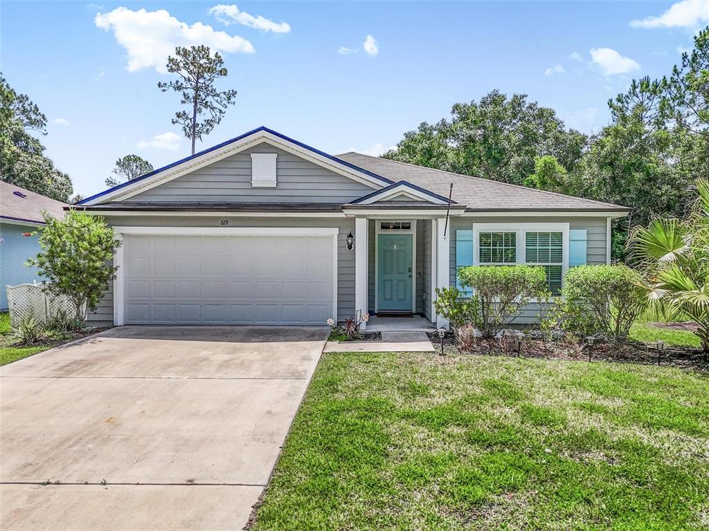 A single-story house with gray siding, a two-car garage, and a light blue front door — 619 GRAND RESERVE DRIVE, BUNNELL, FL