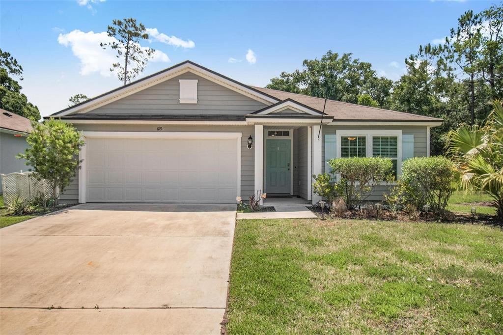 A single-story house with gray siding, a two-car garage, and a light-colored front door — 619 GRAND RESERVE DRIVE, BUNNELL, FL